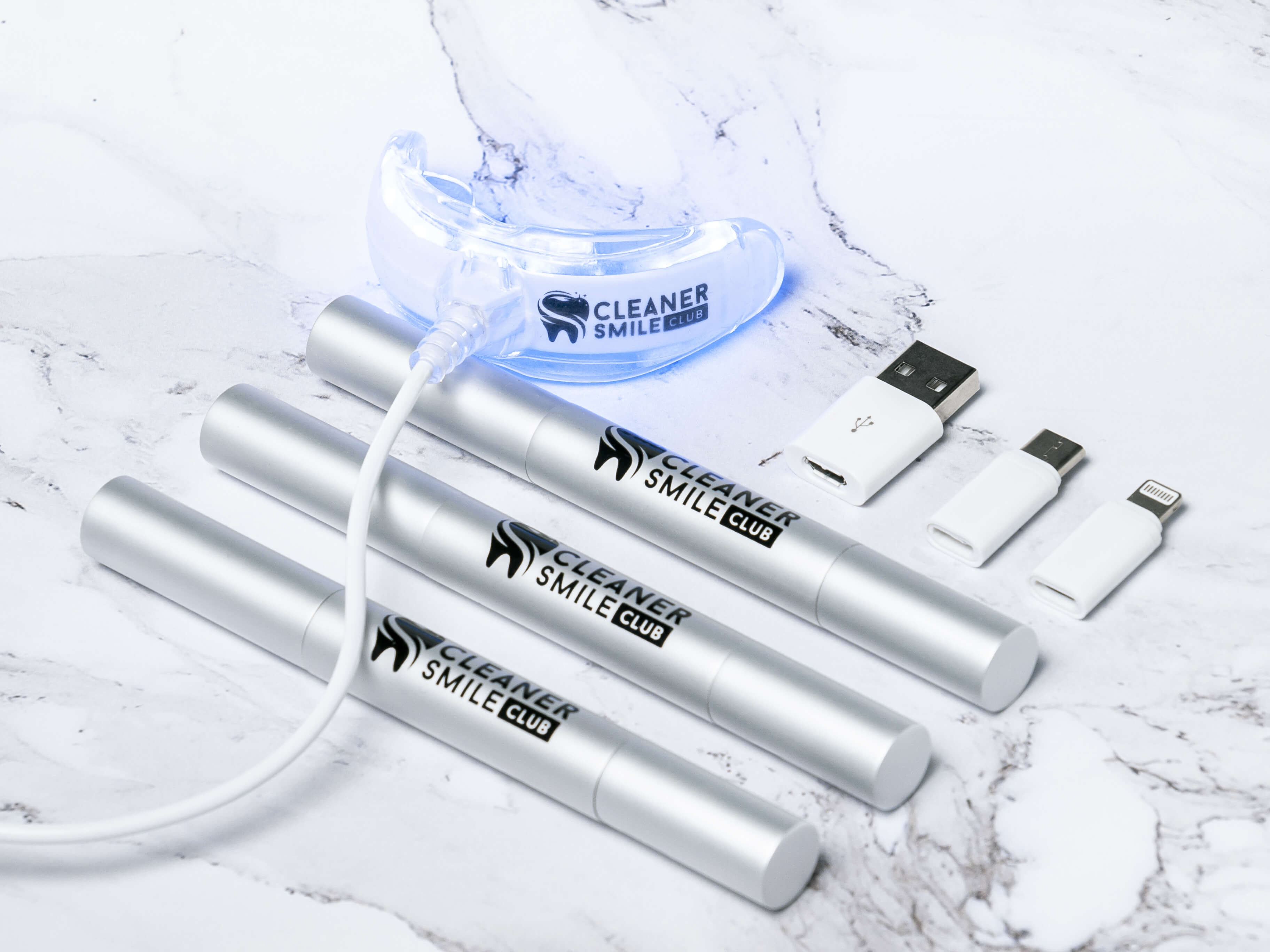 The best ways to whiten teeth are to use teeth whitening black kit from Cleaner Smile Club commercial that consist from 3 silver whitening pens and LED mouth piece with black logo commercial photo made by Fantastic Imago Branding, Advertising and Consulting Agency